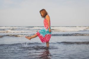 women wearing a dress splashing her feet in the water