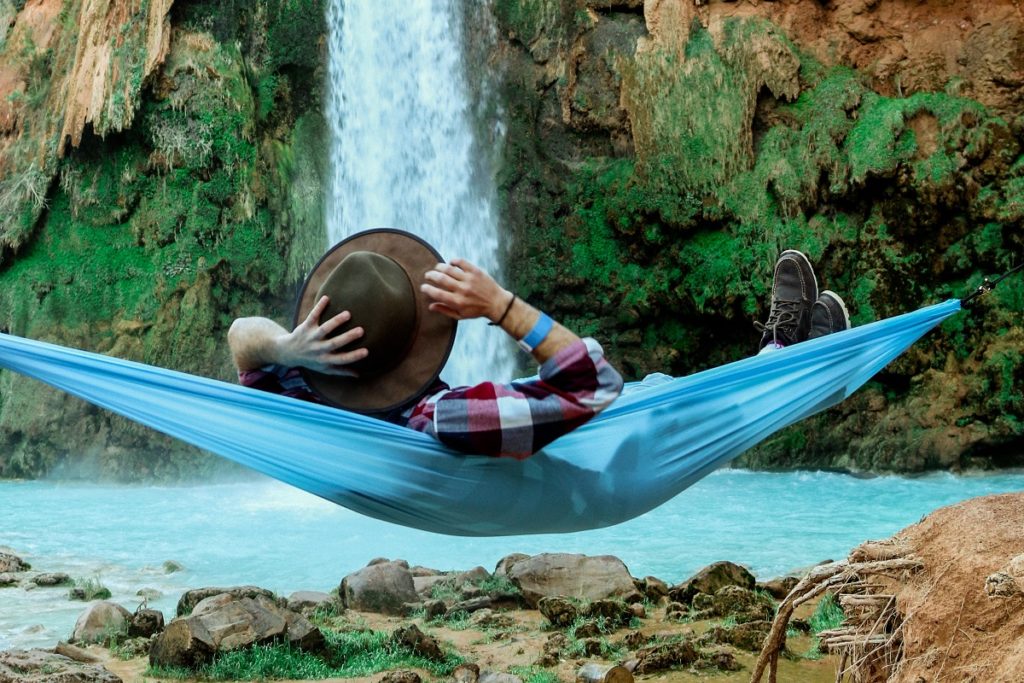 man in hammock by waterfall